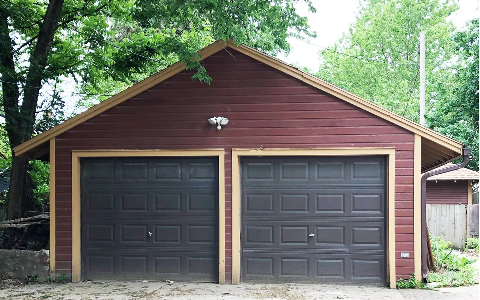 Detached residential garage with dual overhead sectional doors and paneled framing